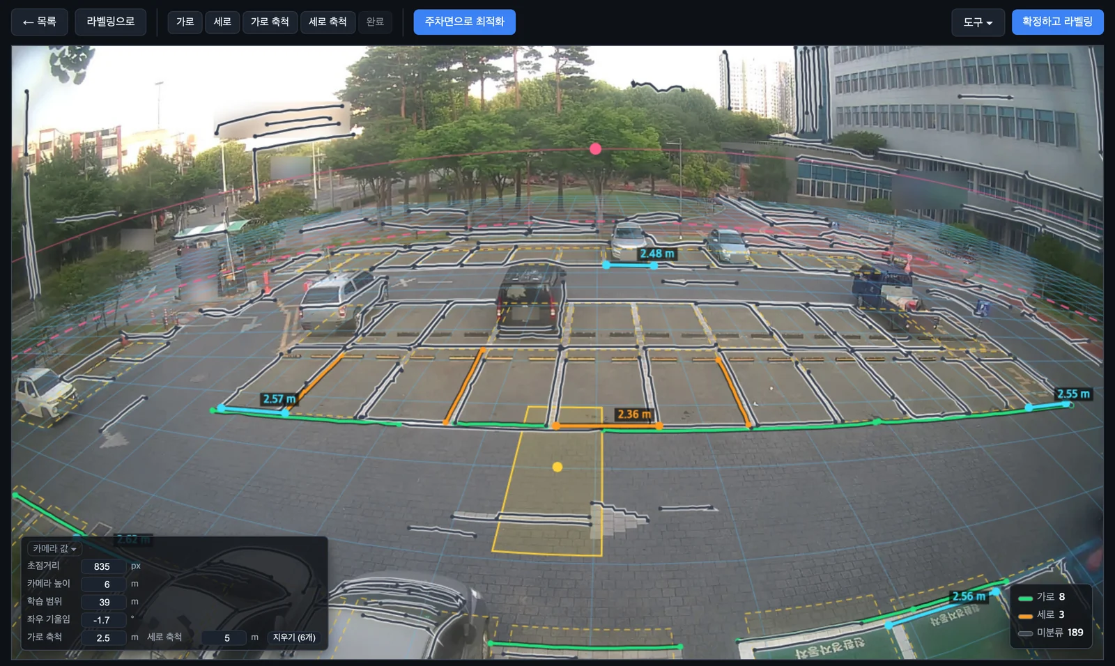 라벨링 도구의 카메라 보정 화면. 야외 주차장 CCTV 사진 위에 주차선을 따라 그은 가로선(초록)·세로선(주황)과 축척선, 바닥에 깔린 격자가 보이고, 왼쪽 아래에 초점거리 835 px·카메라 높이 6 m·좌우 기울임 같은 카메라 값이 있다. 번호판과 사람, 간판은 흐리게 가렸다.